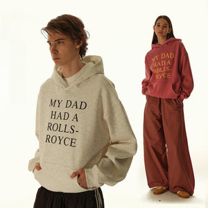 Two people wearing hoodies with humorous text, one beige and one red.